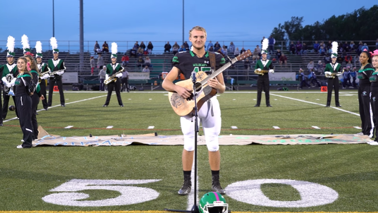Football player removes helmet to sing national anthem when no one else would
